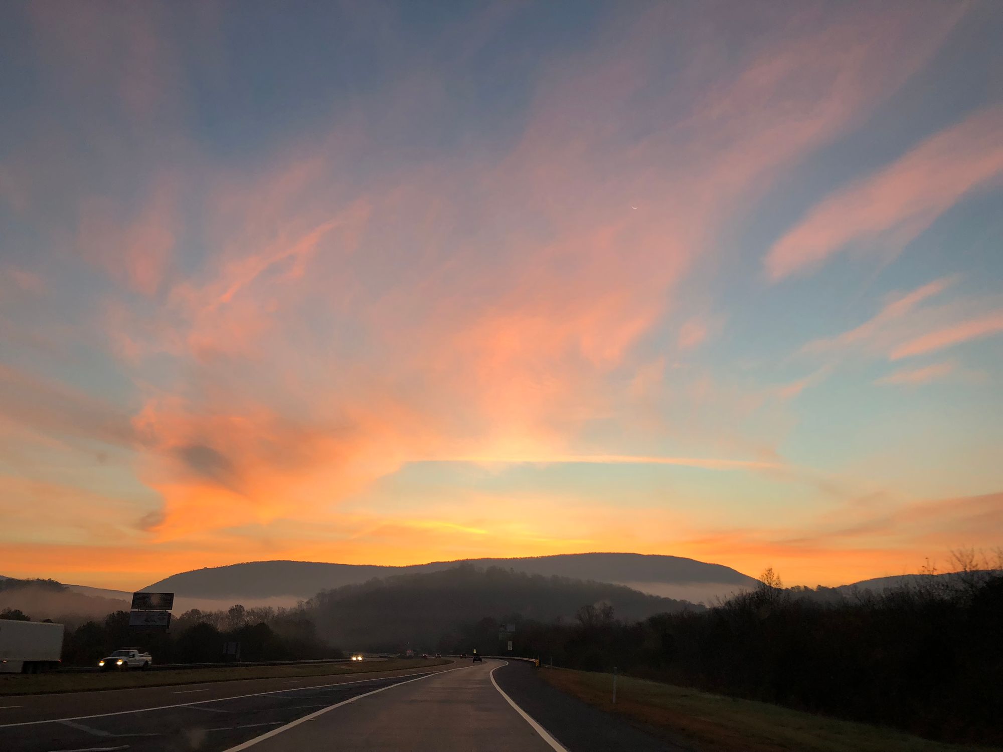 Sunrise over a winding road in Tennessee with mountains in the distance.